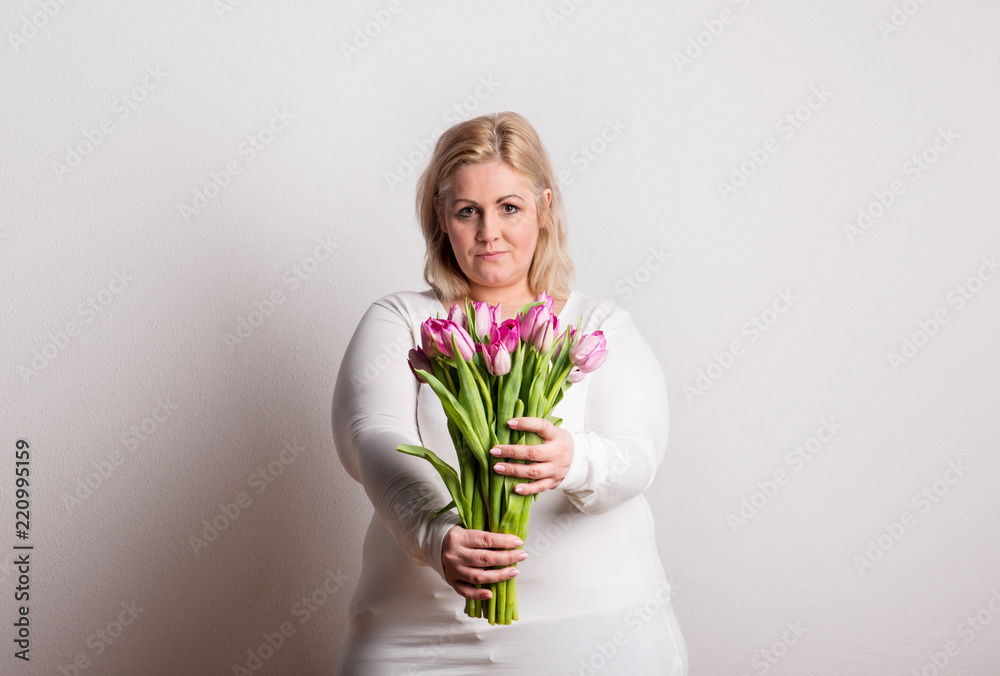 Portrait of an attractive overweight woman with tulips in studio on a white background. Portrait of an attractive overweight woman with tulips in studio on a white background.