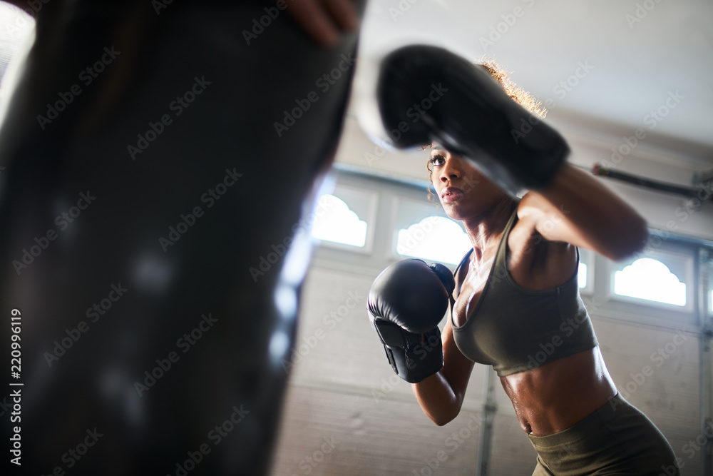 african american woman striking punching bag in home gym