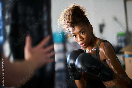 african woman boxing with punching bag in garage gym © Joshua Resnick
