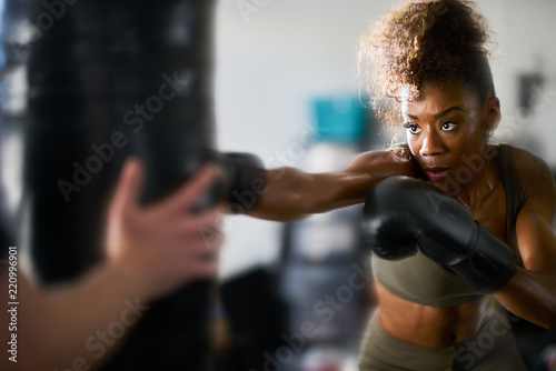 african american woman striking punching bag in home gym © Joshua Resnick