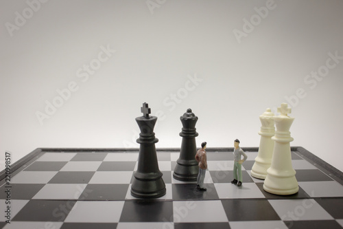 Closeup miniature businessman talking on chess board with chess.