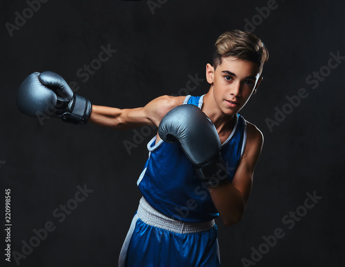 Handsome young boxer during boxing exercises, focused on process. Isolated on the dark background. © Fxquadro