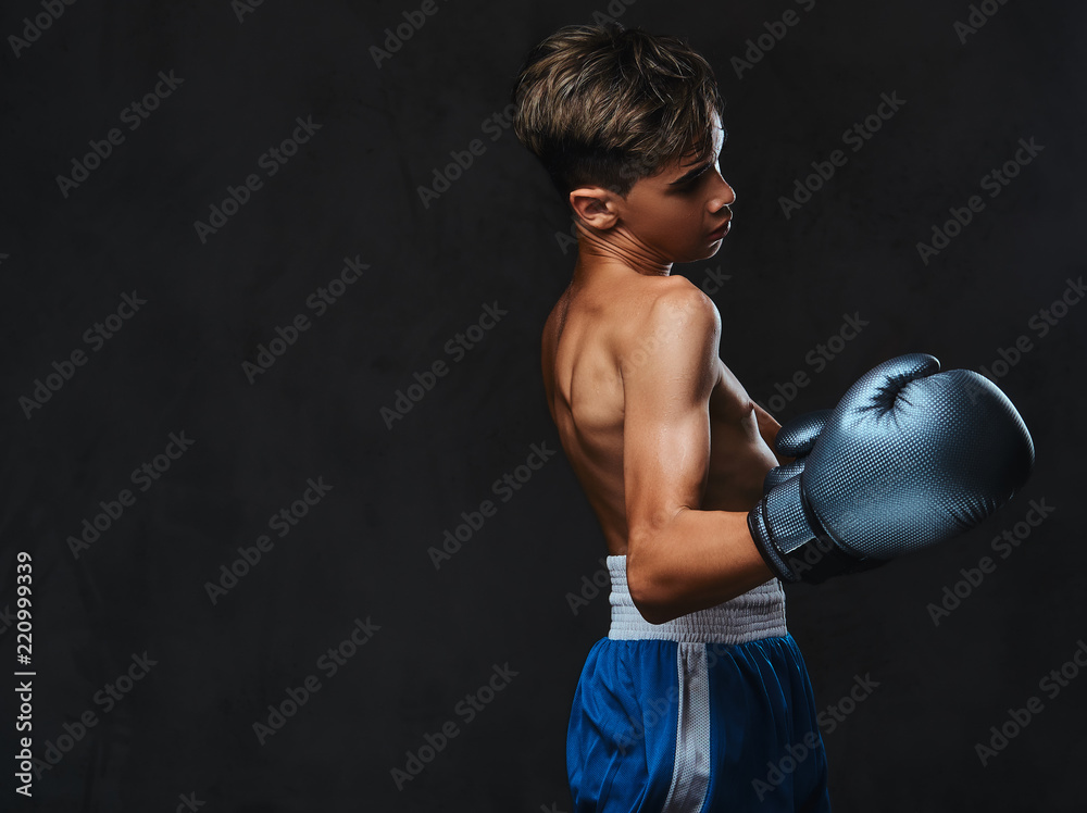 Handsome shirtless young boxer during boxing exercises, focused on process with serious concentrated facial.