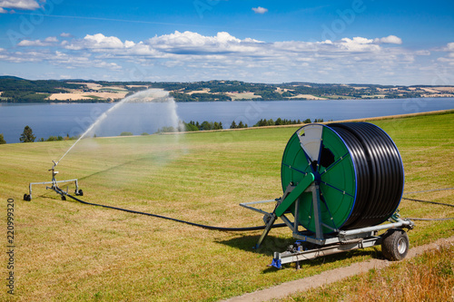 Watering field with travelling sprinkler  irrigation machine during a drought