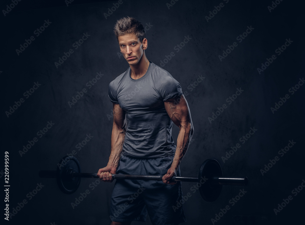 Handsome sportsman with stylish hair dressed in a sportswear doing the exercises with the barbell. Handsome sportsman with stylish hair dressed in a sportswear doing the exercises with the barbell.