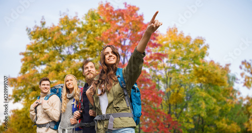 travel  tourism  hike and people concept - group of smiling friends with backpacks hiking over autumn trees background