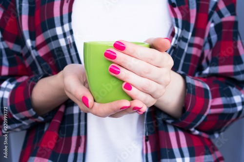 women's hands, girl holding a Cup of coffee or tea, green Cup, side view, close up