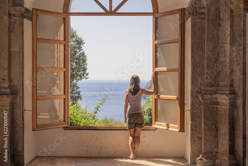 Young woman at a large open window.