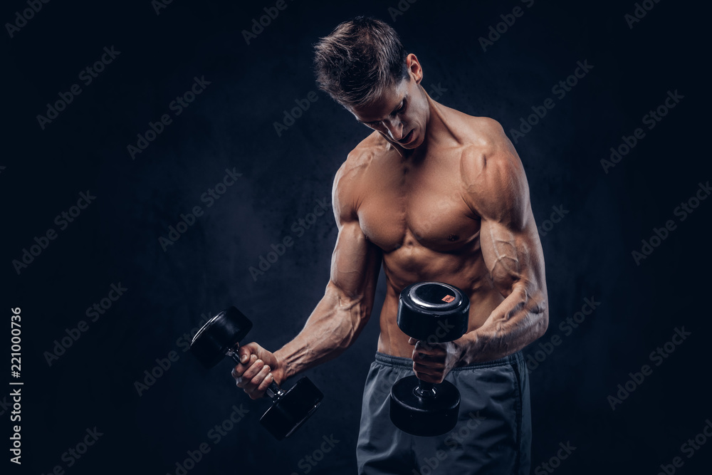 Handsome shirtless man with stylish hair and muscular ectomorph body doing the exercises with dumbbells. Handsome shirtless man with stylish hair and muscular ectomorph body doing the exercises with dumbbells.