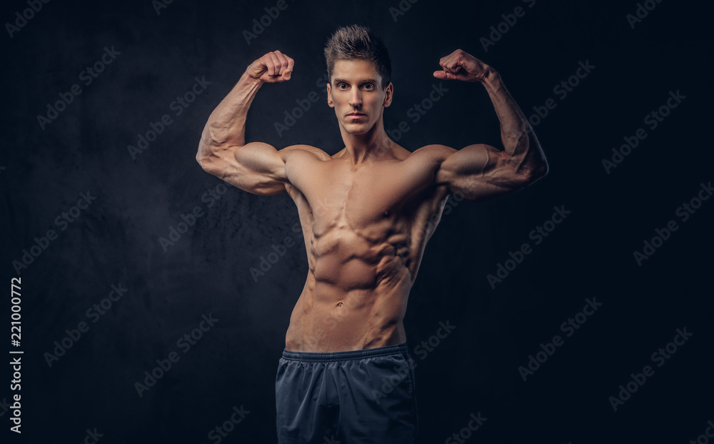 Fototapeta premium Handsome shirtless man with stylish hair and muscular ectomorph shows his biceps.