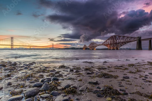 Obraz plaża, woda, dwa mosty i niebo z chmurami