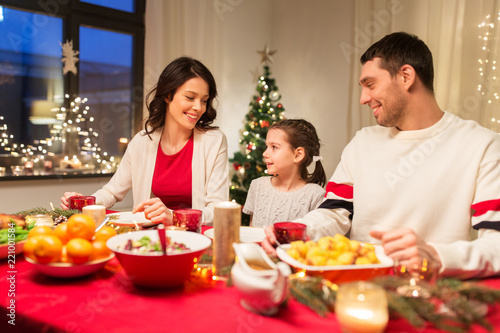 holidays  family and celebration concept - happy mother  father and little daughter having christmas dinner at home