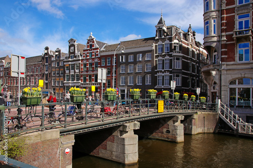 Fototapeta Naklejka Na Ścianę i Meble -  Amsterdam, Blumen auf einer alten Brücke Gracht, blauer Himmel 