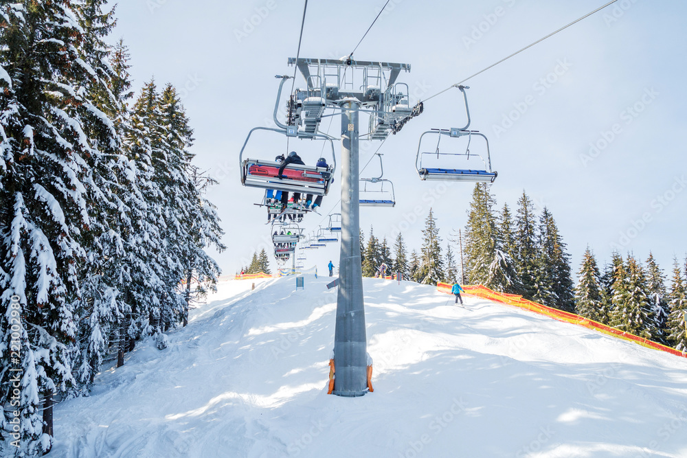 Skiers and snowboarders on a ski lift.view from above on the cable car among the winter forest. Skiers and snowboarders on a ski lift.view from above on the cable car among the winter forest.