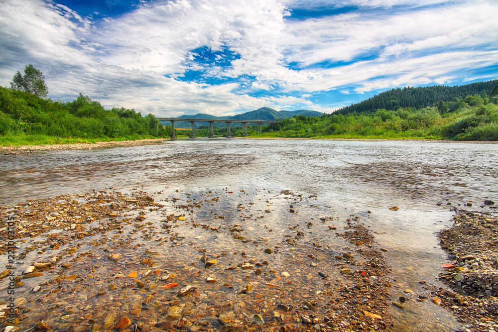 Fototapeta premium Mountain river stream of water in the rocks with majestic blue sky