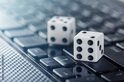 Dice on laptop computer keyboard. Сoncept of online gambling and online casino. Creative idea with devil's bones and PC keyboard.