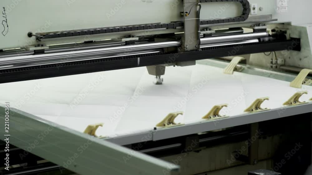 Close-up of automated textile machine quilting white cotton fabric at factory Close-up of automated textile machine quilting white cotton fabric at factory