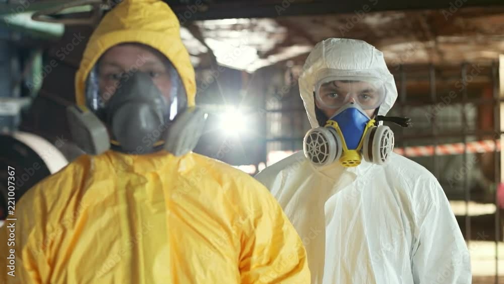 Guys wearing protective uniform looking directly at camera. Two Caucasian men in hazmat suits. Invisible danger. Job. Indoors