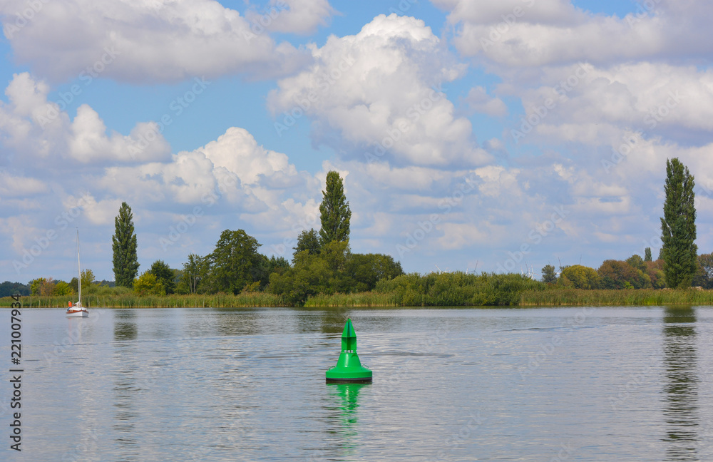Obraz premium Boje und Segelboot auf dem Fluss