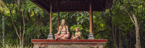 Mom and son meditate practicing yoga in the traditional balinesse gazebo BANNER, long format photo