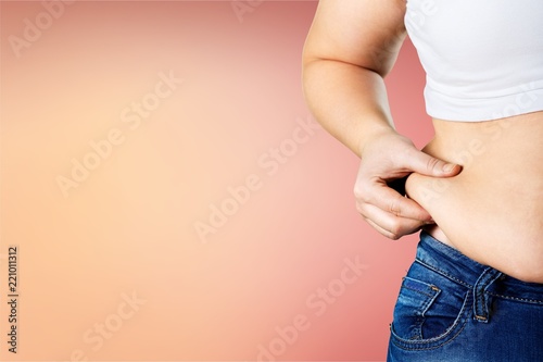Woman's hand holding excessive belly fat photo