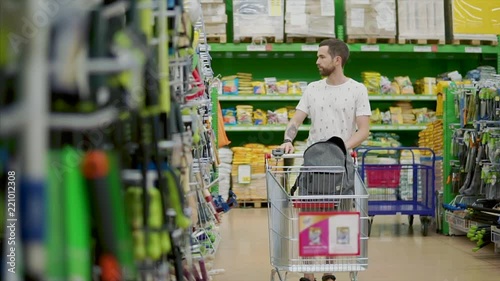 Wallpaper Mural Young customer pushing shopping cart along aisle with tools and gardening tools, man shopping in hardware department store. Empty cart. Torontodigital.ca