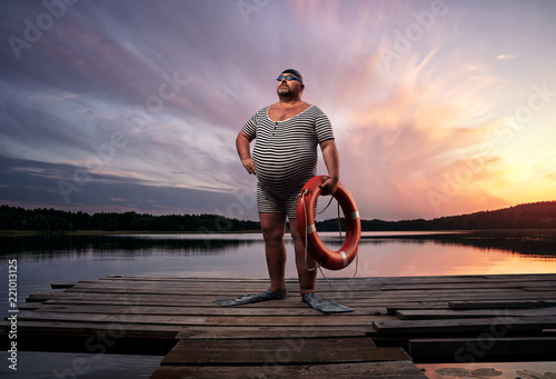 Fuunny overweight, retro swimmer by the lake, at the sunset with copy space