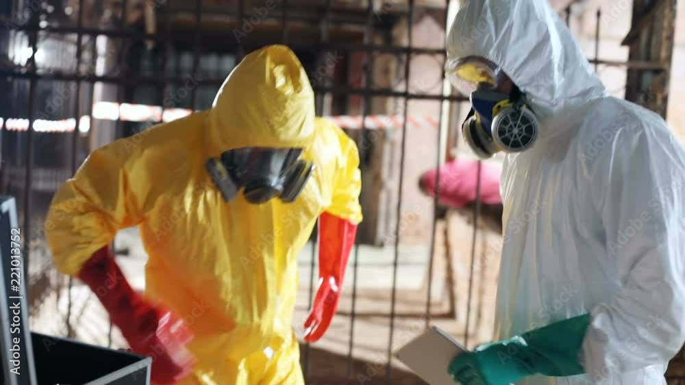 Two young Caucasian men wearing colored hazmat suits in abandoned ...