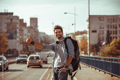 Young man traveler hitchhiking in the city
