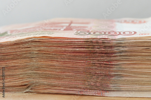 Big stack of Russian money banknotes of five thousand rubles lying on a wooden table