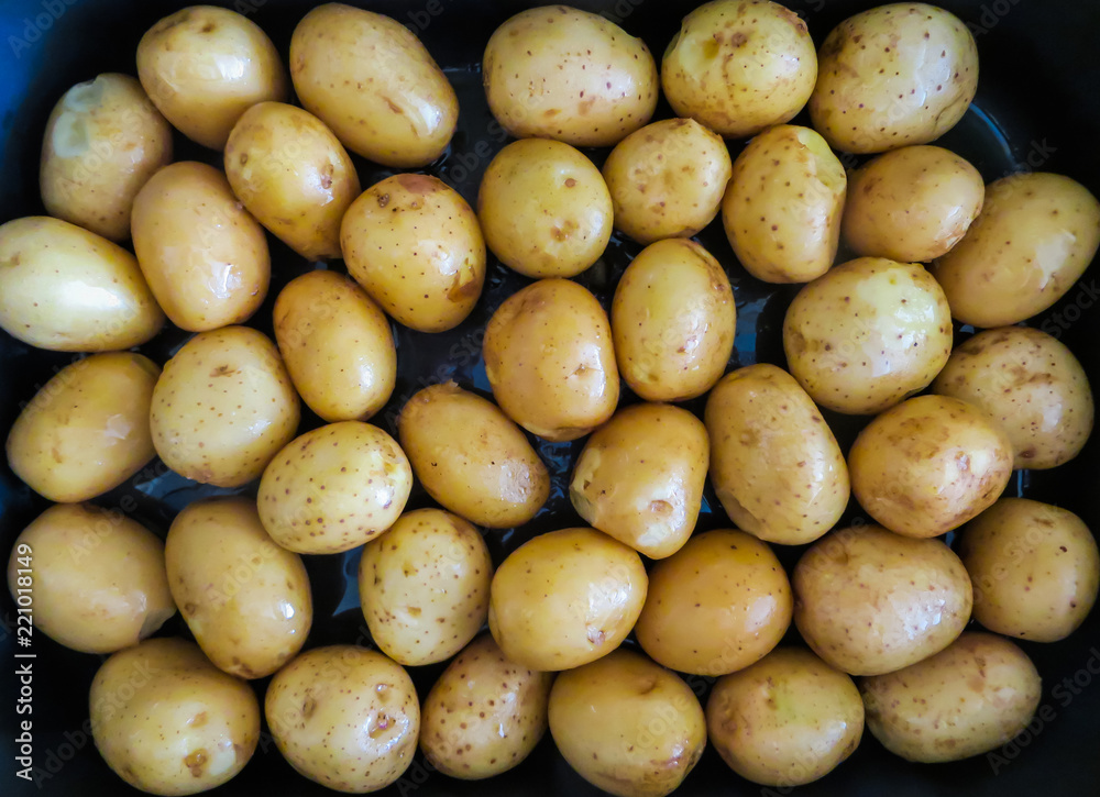 young, delicious potatoes in the form for baking, poured with olive oil young, delicious potatoes in the form for baking, poured with olive oil