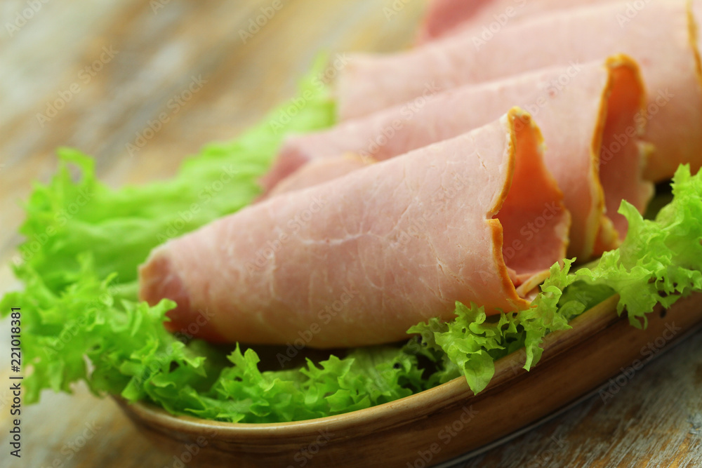 Slices of tasty ham on fresh lettuce leaves, closeup
Slices of tasty ham on fresh lettuce leaves, closeup