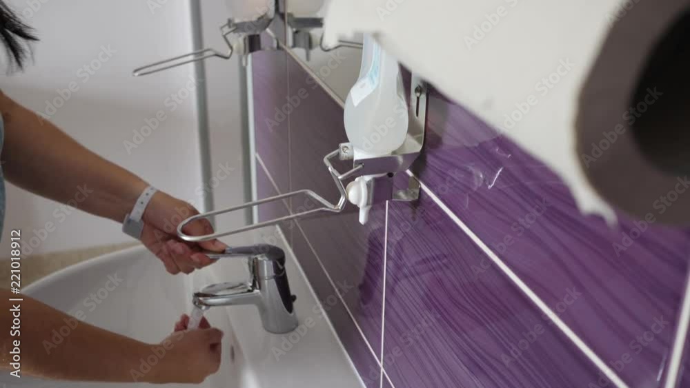 Woman patient in hospital room washes hands with soap and wipes with paper towels Woman patient in hospital room washes hands with soap and wipes with paper towels