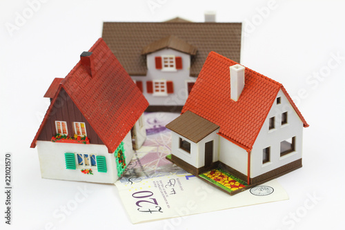 Three model houses on British pound banknote on white background
