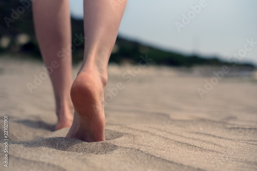 Bare feet of women walking on the sand on the beach by the sea