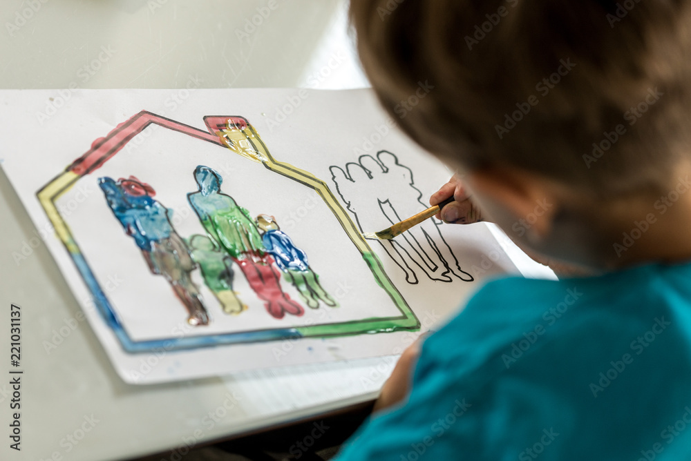 Child colouring in a sketch of a family using a paintbrush Child colouring in a sketch of a family using a paintbrush