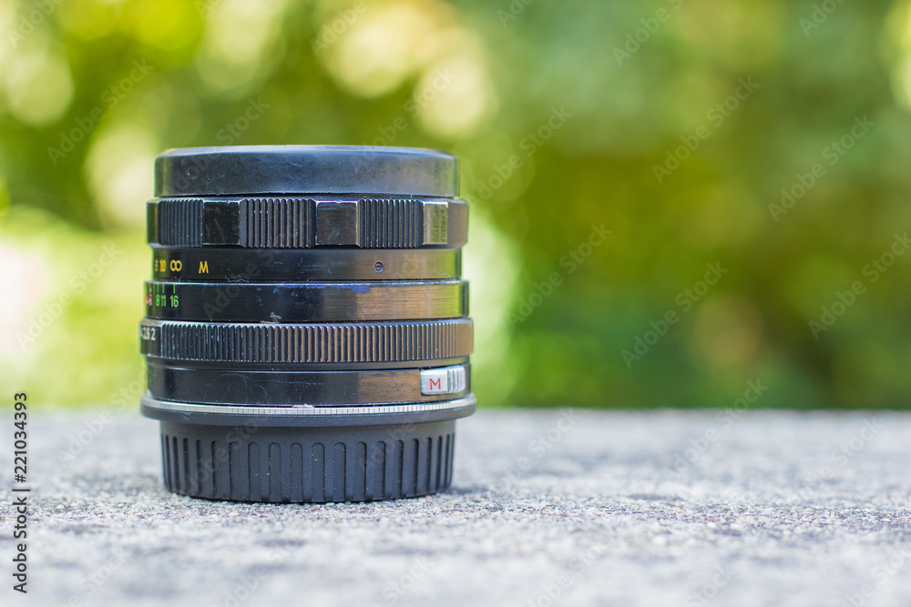old USSR camera lens object shot concept on natural blurred unfocused bokeh green background with empty copy space for your text old USSR camera lens object shot concept on natural blurred unfocused bokeh green background with empty copy space for your text