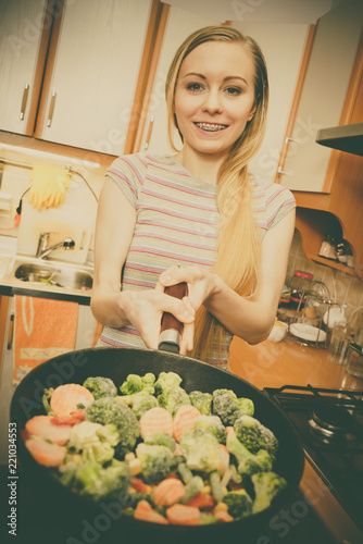 Woman cooking stir fry frozen vegetable on pan
