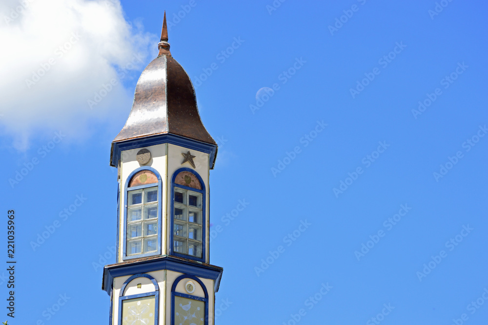 Interesting tower with the moon and clouds in a blue sky background Interesting tower with the moon and clouds in a blue sky background