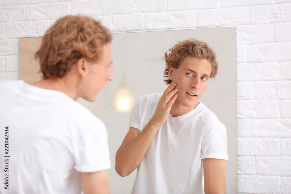 Young man looking in mirror after shaving at home Young man looking in mirror after shaving at home
