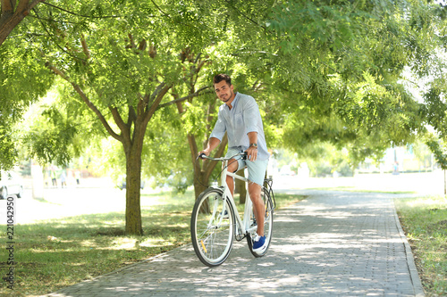 Handsome young hipster man riding bicycle in park