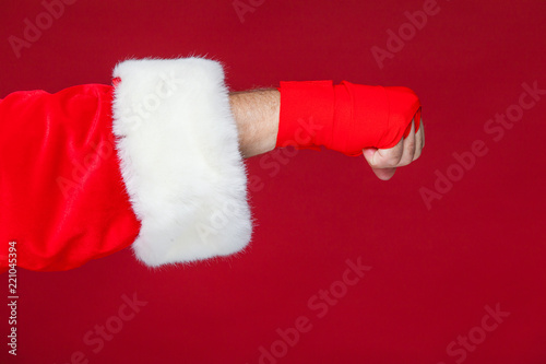 Christmas. Santa Claus fist with red bandages wound for boxing. Kickboxing, boxing, karate. Isolated on red background.