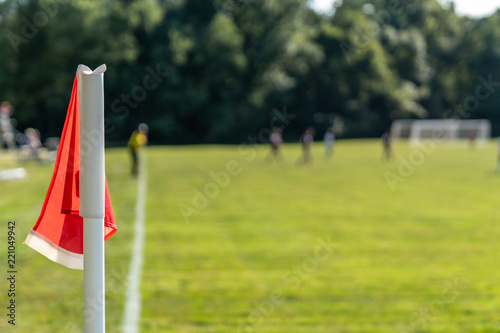 Orange Corner Flag Close Up with College Youth Playing Soccer with Trees in Background of Field
