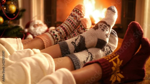 Closeup 4k video of family with child wearing warm wool socks lying by the fireplace on Christmas eve