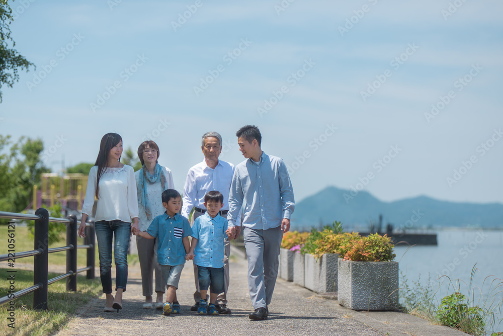 手を繋いで公園を歩く三世代家族