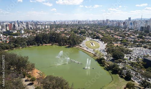 Aerial view of Ibirapuera park in Sao Paulo city, Monument to the Bandeiras. Prevervetion area with trees and lake of Ibirapuera park. Office buildings and residential district in the background.