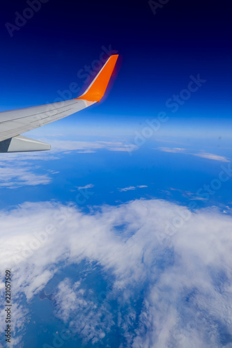 airplane wing over the blue cloud sky