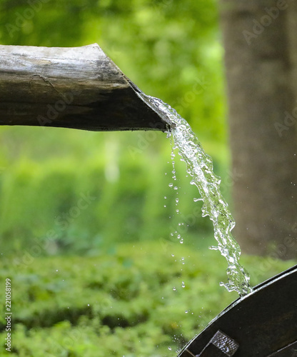 water flows from a wooden pipe or water gushing out of the pipe close up