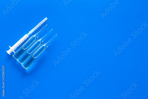 Flu vaccination concept. Syringe and ampoulie on blue background top view copy space
