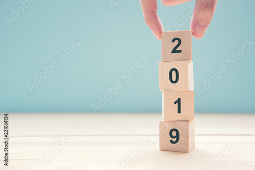 Hand of man putting wood cube shape with text new year 2019, copy space.